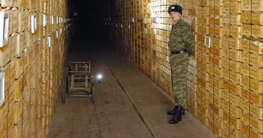 A soldier standing in a dark tunnel filled with stacked wooden ammunition crates in Cobasna.