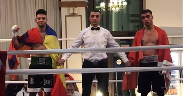 Two boxers standing in a boxing ring with a referee between them.