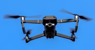A DJI Mavic 2 drone flying in a clear blue sky.