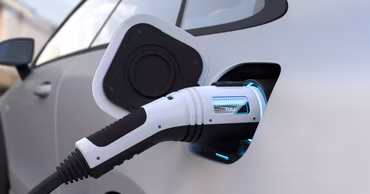 A close-up of an electric car being charged with a plug.