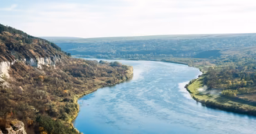 A scenic view of the Dniester River flowing through a valley with rocky cliffs and greenery.