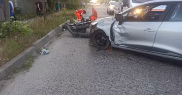 A damaged car and motorcycle at an accident scene with emergency responders present.