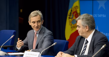 Iurie Leanca participating in an official meeting with the Moldovan flag in the background.
