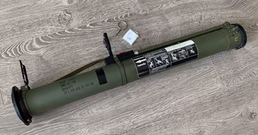 An RPG-26 anti-tank grenade launcher lying on a wooden floor.