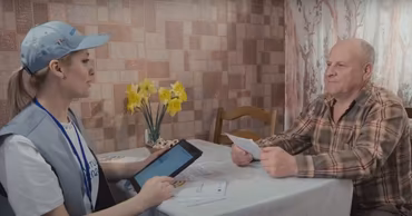 A census worker from the Moldovan National Bureau of Statistics interviewing an elderly man at home.
