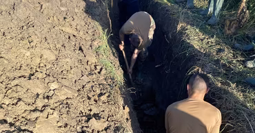Moldovan carabineers and workers digging and reinforcing a dam to prevent flooding.