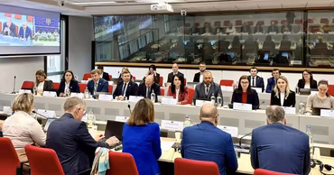 Government officials attending a formal meeting in a conference room.