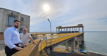 Two men standing at the Costesti hydropower plant facility.