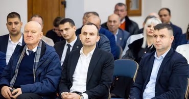 Paul Gamurari sitting in a formal setting among other attendees at an event.