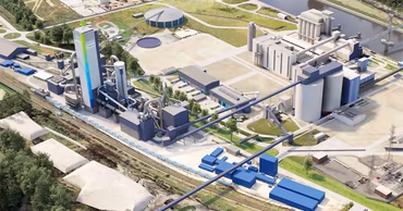Aerial view of a large industrial cement manufacturing plant with silos and processing buildings.
