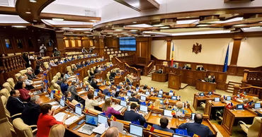 Wide angle view of the Moldovan Parliament plenary hall with members seated at their desks.