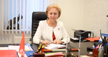 Zinaida Croitor sitting at her office desk writing in a notebook.