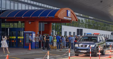 Exterior view of Chisinau International Airport with passengers and a border police vehicle.