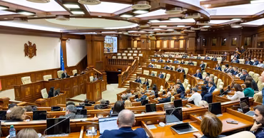 A wide shot of the Moldovan Parliament plenary session hall with deputies at their desks.
