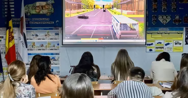 Students sitting in a driving school classroom watching a traffic simulation on a projector screen.