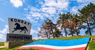 Entrance sign to Comrat, Gagauzia, with the regional flag and a horse emblem.