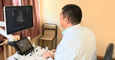 A doctor in a white coat performing an ultrasound examination on a patient.