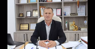 Sergei Anastasov sitting at his desk in an office with diplomas on the shelves behind him.