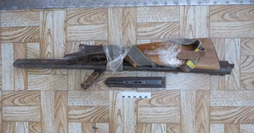 A disassembled homemade firearm lying on a wooden floor, likely evidence from a police investigation.