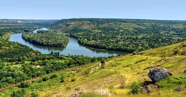 A scenic landscape view of the Dniester River winding through a green valley in Moldova.