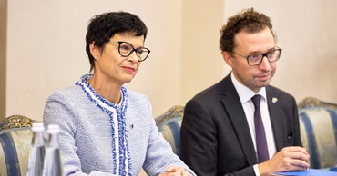 European Commissioner Marta Kos sitting at a meeting table.