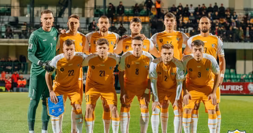 The Moldovan national football team posing for a group photo on the pitch before a match.