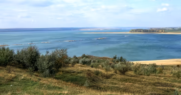 A scenic view of the Costesti-Stanca reservoir with grassy hills in the foreground.
