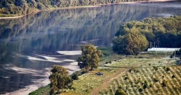 Aerial view of the Dniester River flowing through a rural landscape with trees and fields.