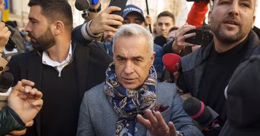 Calin Georgescu surrounded by journalists and microphones in a public setting.