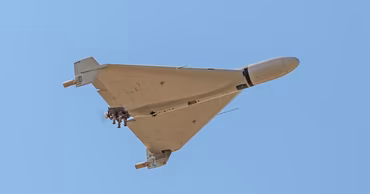 A Shahed-type military drone flying in a clear blue sky.