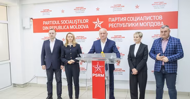 Igor Dodon and other PSRM party members standing at a press conference podium.