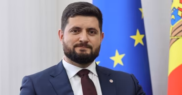 Portrait of Dorin Jungietu in front of the European Union and Moldovan flags.