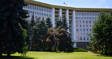 The Parliament building of the Republic of Moldova in Chisinau surrounded by trees.