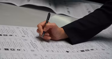 A person's hand marking a Moldovan election ballot paper with a pen.