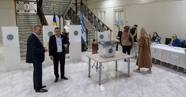 People at a polling station in Moldova with ballot boxes and voting booths.