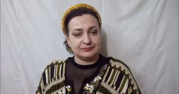 A portrait of Olga Arseni wearing a decorative headband and patterned clothing.