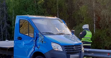 A damaged blue truck at a roadside accident scene with a responder in a high-visibility vest.