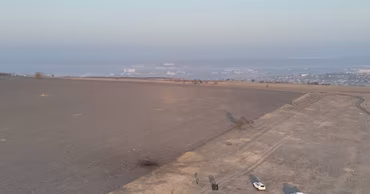 Aerial view of a field in Moldova with police vehicles and personnel investigating drone debris.