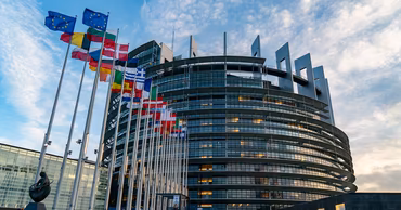 The European Parliament building in Strasbourg with European Union member state flags flying outside.