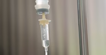 A close-up of an intravenous drip bag and tubing in a hospital setting.