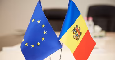 Flags of the European Union and Moldova placed side by side on a table.