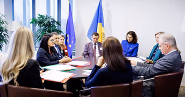 A group of officials sitting around a conference table with Moldovan and EU flags.