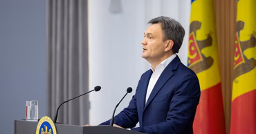 Dorin Recean speaking at a podium with the Moldovan government emblem and flags.
