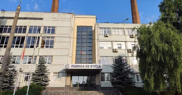 The main building of the Chisinau Glass Factory with industrial chimneys in the background.