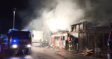 Moldovan firefighters working at a night fire scene with a fire truck and smoke.