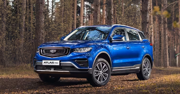 A blue Geely Atlas Pro SUV parked in a forest setting.
