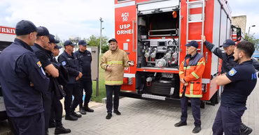 Moldovan emergency responders standing near a fire truck during a training session.
