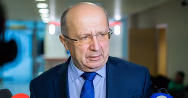 Andrius Kubilius speaking to journalists with microphones in front of him.