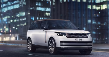A white Range Rover driving on a city street at night.