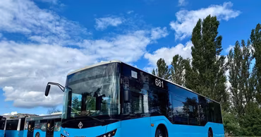 A blue Isuzu bus parked outdoors under a blue sky.